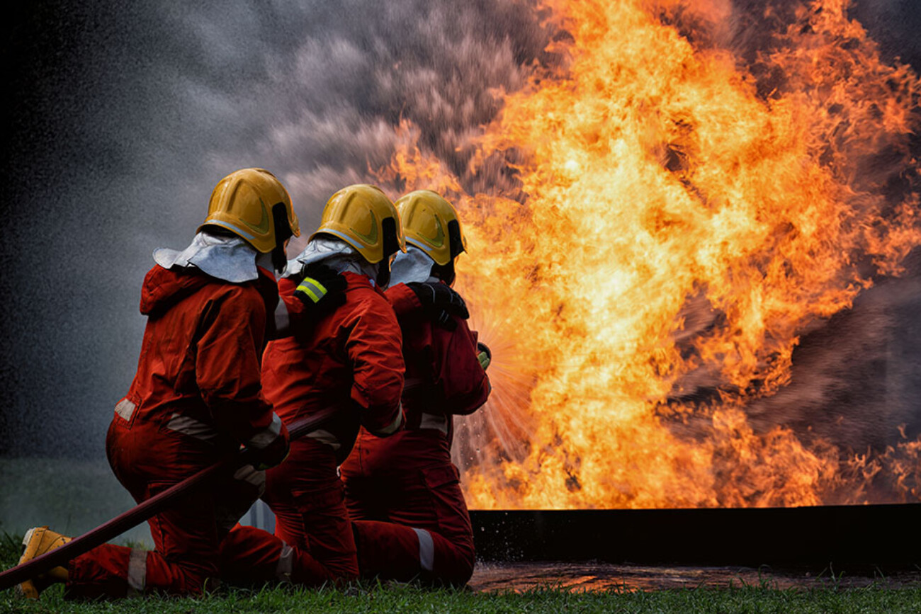 fire fighter team on training with gas and oil fire hold hose spray jet water spray to extinguish